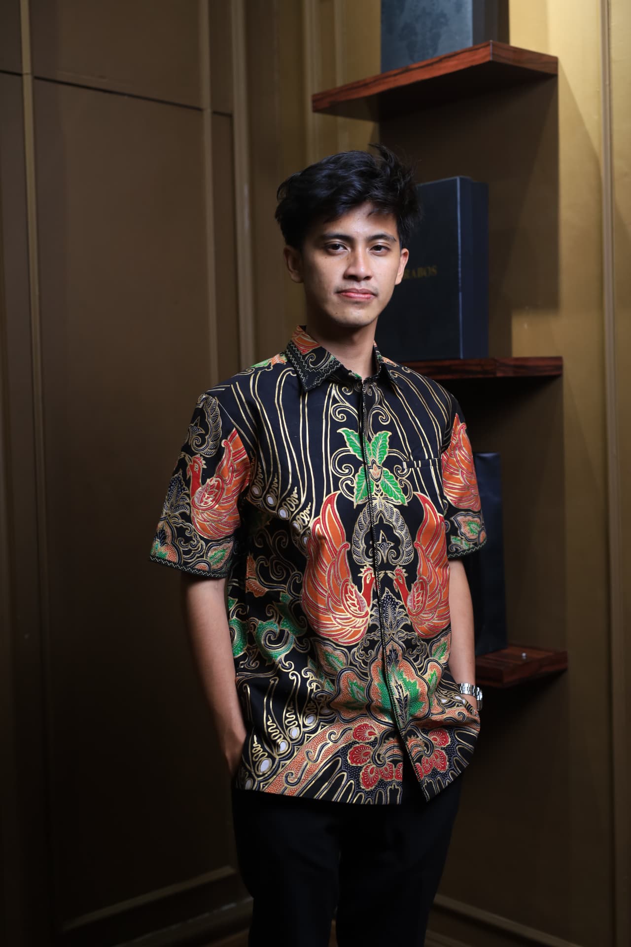 Hem Ayam Gurdo Prada — Hem batik tulis lengan pendek motif ayam gurdo prada dengan warna merah, hijau, dan emas dikenakan model